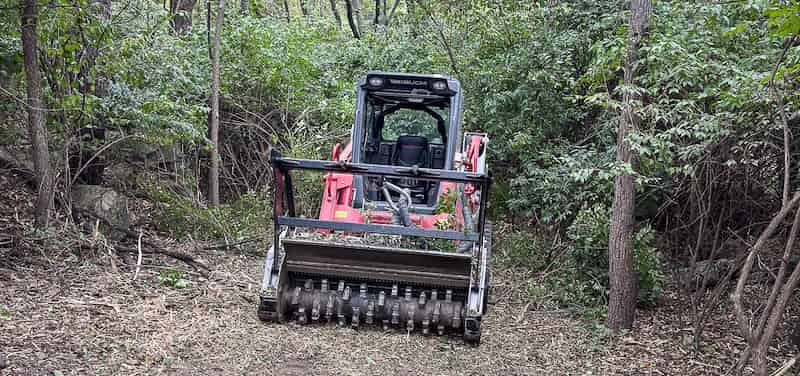 POV view of track loader with forestry mulcher attachment clearing brush
